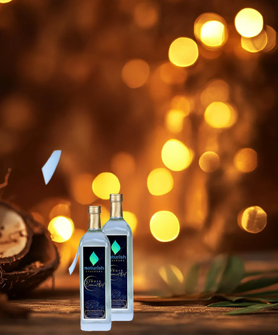 Two Naturish coconut oil bottles on a wooden surface with warm golden bokeh lights creating a festive background.