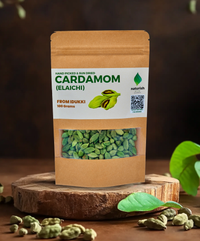 Naturish hand‑picked sun‑dried cardamom (elaichi) 100 g stand‑up kraft pouch displayed on a wooden slice with scattered green cardamom pods and leaves.