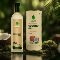 Naturish Elite cold-pressed coconut oil bottle and 1 litre tin on moss with coconut halves in a lush green natural setting.